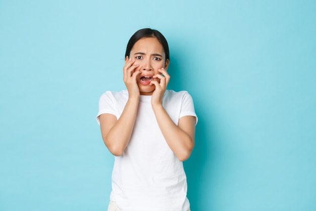 Studio shot of horrified ambushed asian woman in white t-shirt