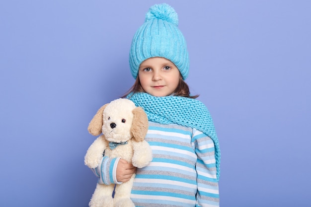 Studio shot of little girl with her soft dog toy in hands