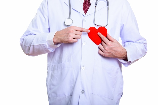 Studio shot of mature man doctor holding red heart against chest