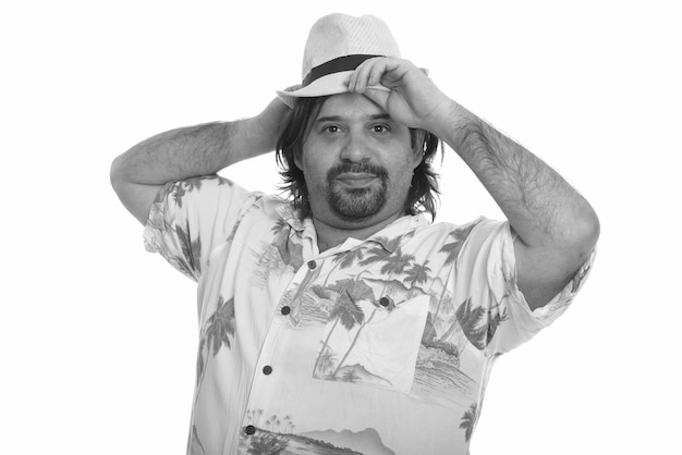 Studio shot of overweight bearded tourist man ready for vacation isolated against white background in black and white