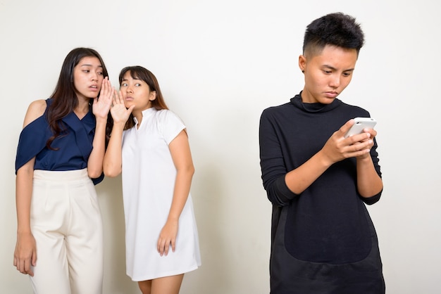 Studio shot of three young beautiful Asian women as friends together against white background