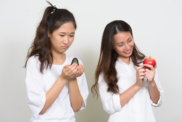 Studio shot of two young beautiful Korean women as friends together against white background