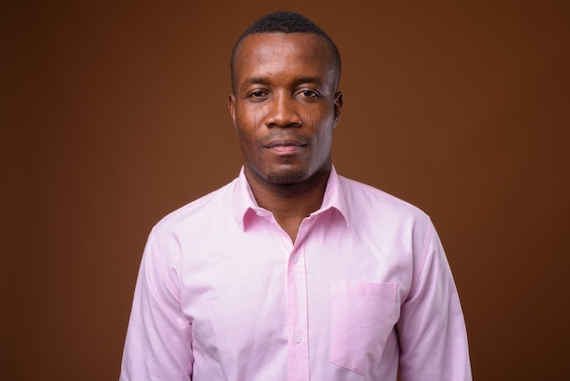 Studio shot of young African businessman against brown background