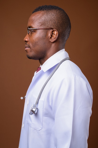 Studio shot of young African man doctor against brown background