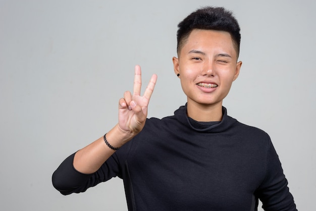 Studio shot of young Asian lesbian woman with short hair against white background