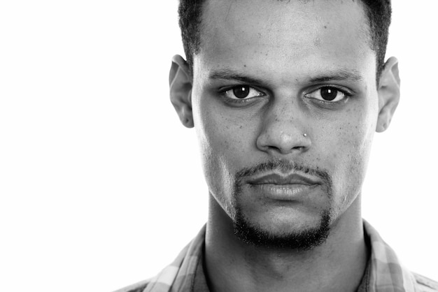 Studio shot of young bearded African businessman with afro hair isolated against white background in black and white