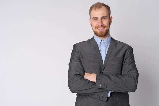 Studio shot of young bearded businessman wearing suit against white