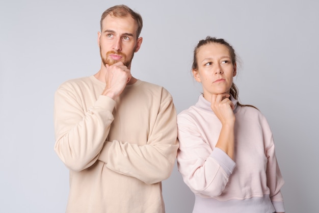 Studio shot of young bearded man and young beautiful woman together against white