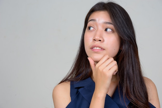 Studio shot of young beautiful Asian businesswoman against white background