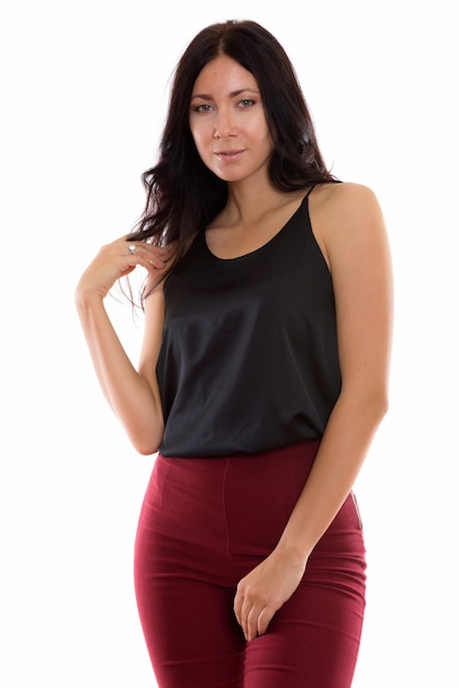 Studio shot of young beautiful businesswoman standing while touching her hair