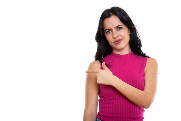 Studio shot of young beautiful Spanish woman pointing at side