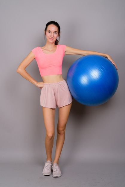 Studio shot of young beautiful woman ready for gym against gray