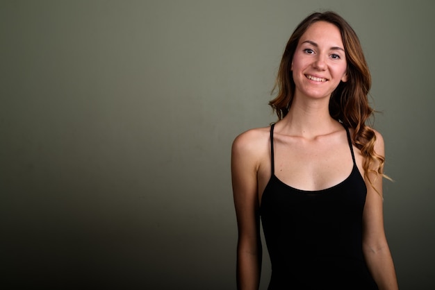 Studio shot of young beautiful woman wearing sleeveless top against colored background