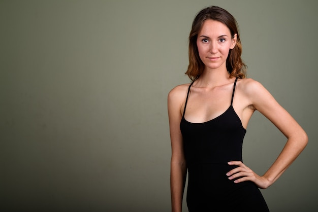 Studio shot of young beautiful woman wearing sleeveless top against colored background