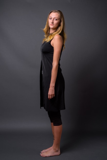 Studio shot of young beautiful woman with straight blond hair against gray