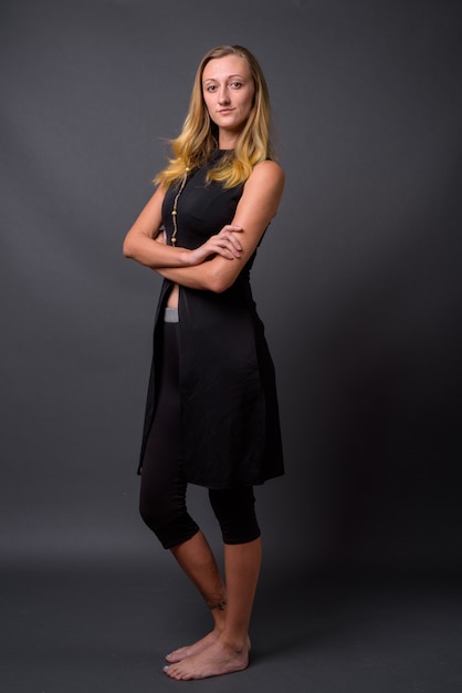 Studio shot of young beautiful woman with straight blond hair against gray