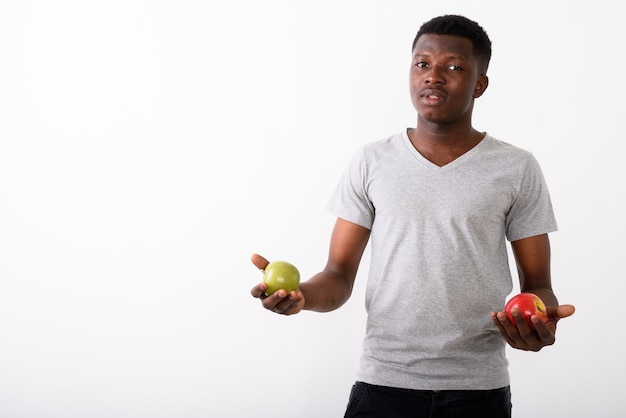 Studio shot of young black African man holding red apple and green