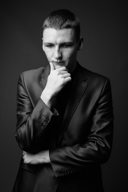 Studio shot of young businessman wearing suit against grey wall