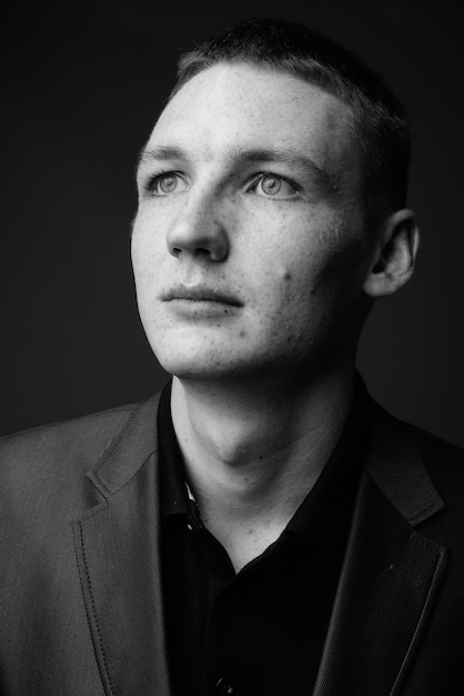 Studio shot of young businessman wearing suit against grey wall