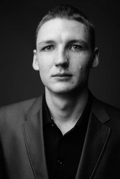 Studio shot of young businessman wearing suit against grey wall