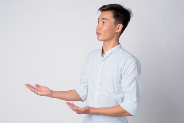 Studio shot of young handsome Asian businessman against white background