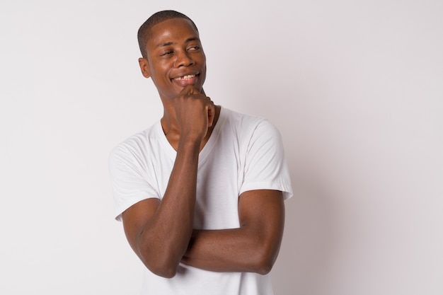 Studio shot of young handsome bald African man against white background