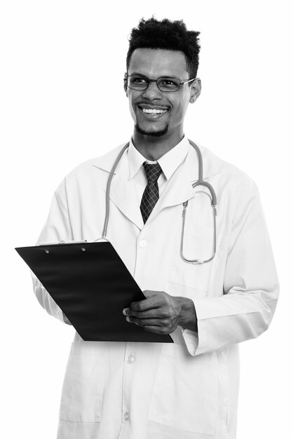 Photo studio shot of young handsome bearded african man doctor isolated against white background in black and white