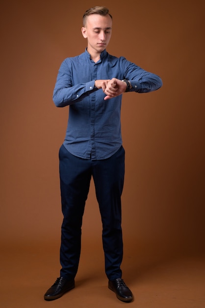 Photo studio shot of young handsome businessman against brown