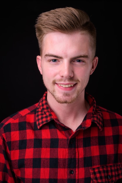 Studio shot of young handsome man against black background