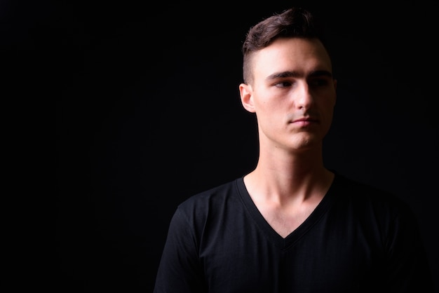 Studio shot of young handsome man against black background