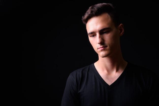 Studio shot of young handsome man against black background