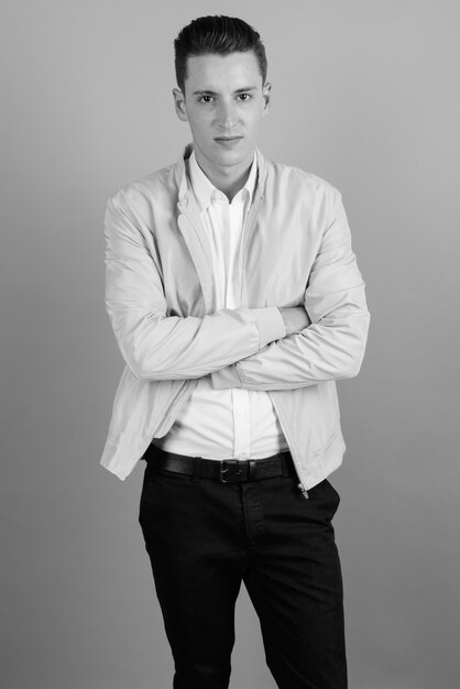 Studio shot of young handsome man against gray background in black and white