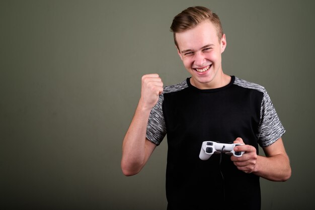 Studio shot of young handsome man with blond hair against colored background