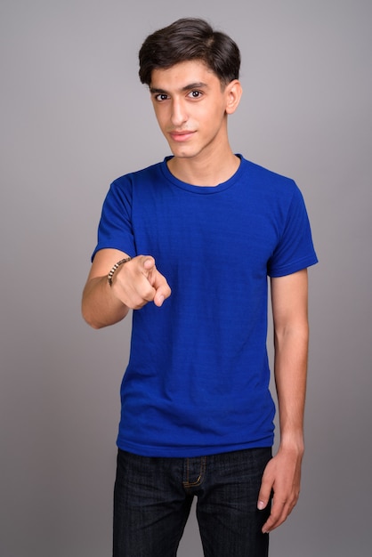 Studio shot of young handsome Persian teenage boy against gray background