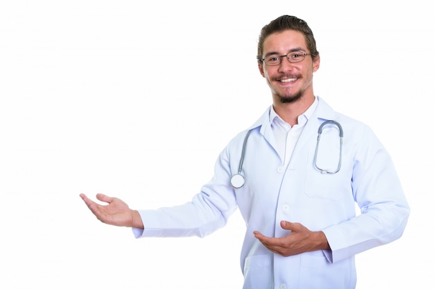 Studio shot of young happy man doctor smiling while showing something