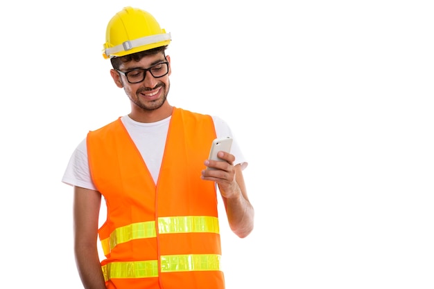 Studio shot of young happy Persian man construction worker smili