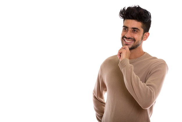 Studio shot of young happy Persian man smiling while thinking a