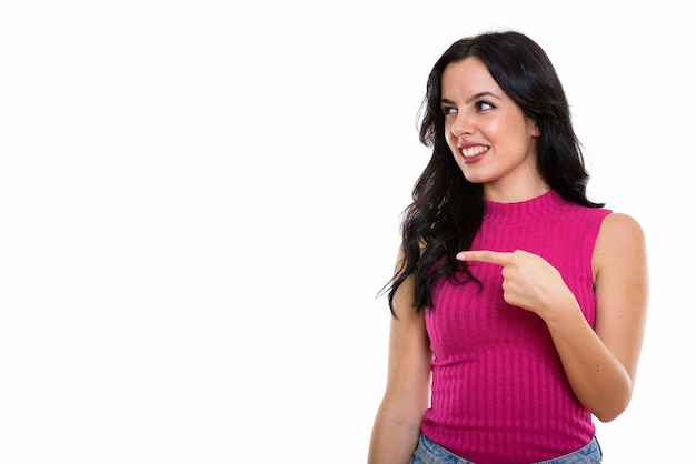 Studio shot of young happy Spanish woman smiling while pointing