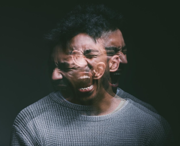 Studio shot of a young man experiencing mental anguish and screaming against a black background