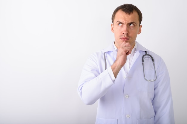 Studio shot of young muscular man doctor thinking while looking