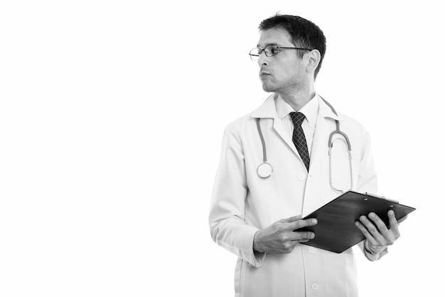 Studio shot of young skinny man doctor with eyeglasses isolated, black and white