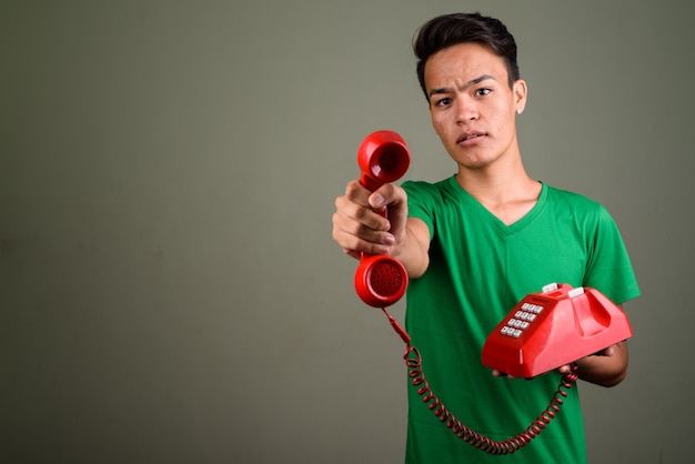 Studio shot of young teenage man wearing green shirt against colored