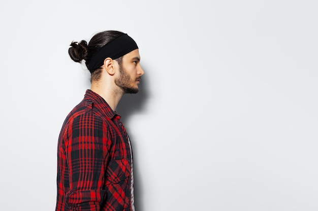 Studio side portrait of young guy with hair bun on white background