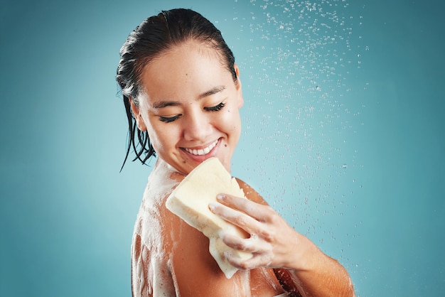 Studio skincare and woman in shower with sponge isolated on a blue background mockup Water splash cleaning or healthy hygiene of female model bathing washing or showering for beauty and body care