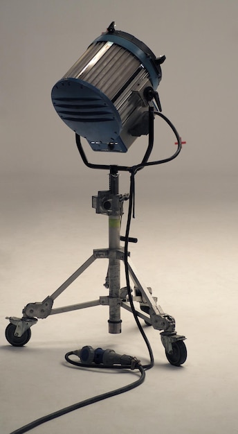 Photo studio spotlight big size equipment on the tripod in a huge studio with green screen background .