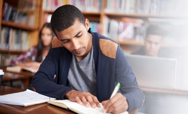 Study writing and school with man in library for education research and classroom quiz Focus learning and notebook with male student on university campus for knowledge scholarship and project