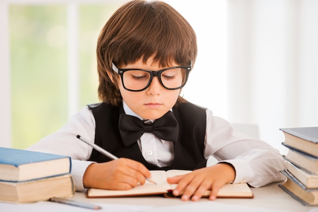 Studying hard. Cute young boy making research while sitting at the desk