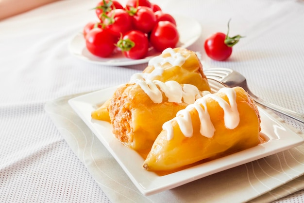 Stuffed bell pepper with meat and rice on a white square plate