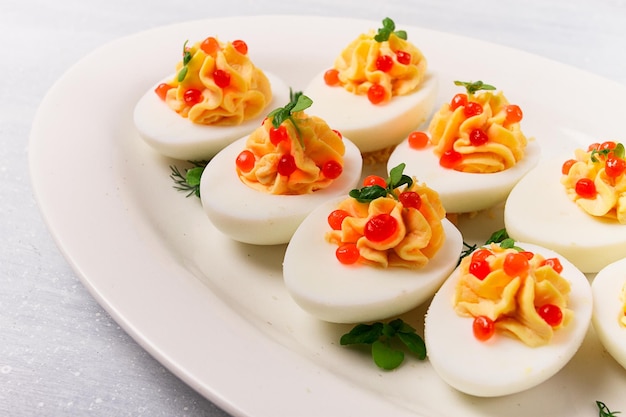 Stuffed eggs with red caviar micro greenery Snack on a white plate top view closeup no people