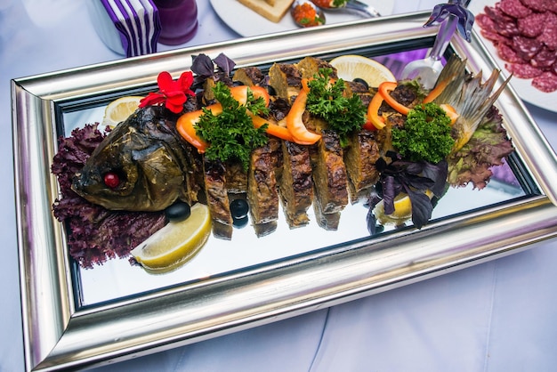 Stuffed fish on a tray with vegetables lemon and basil